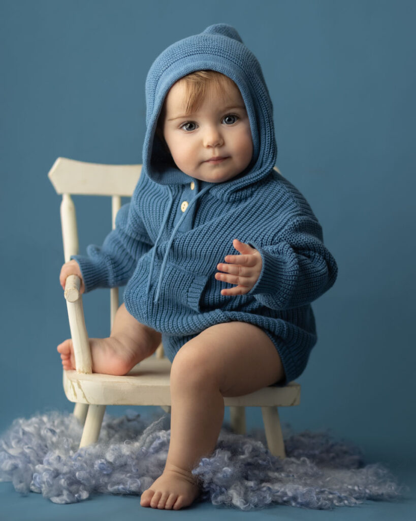 6 - month - old girl in blue knit hoodie during studio milestone session