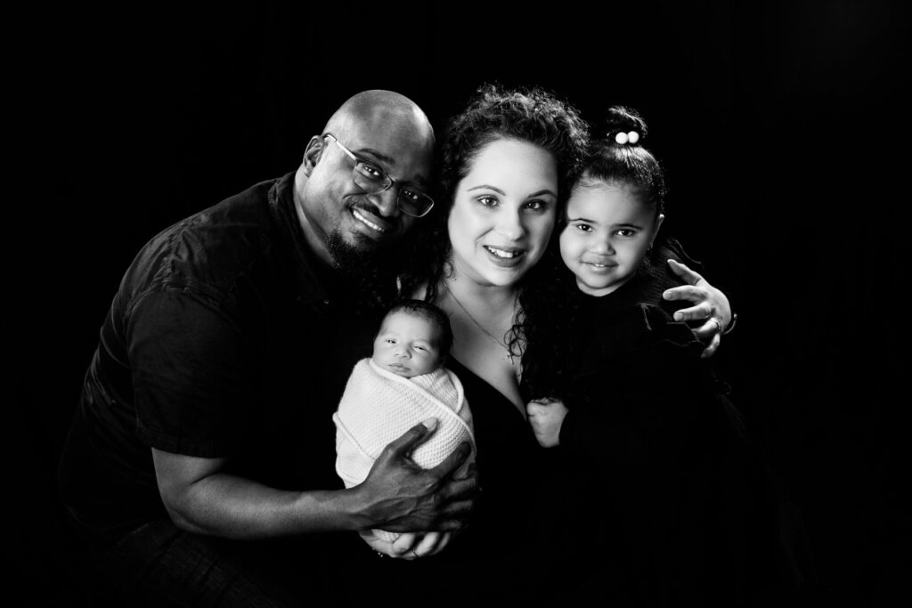 Parents, newborn baby and older sister during a black-and-white family portrait session