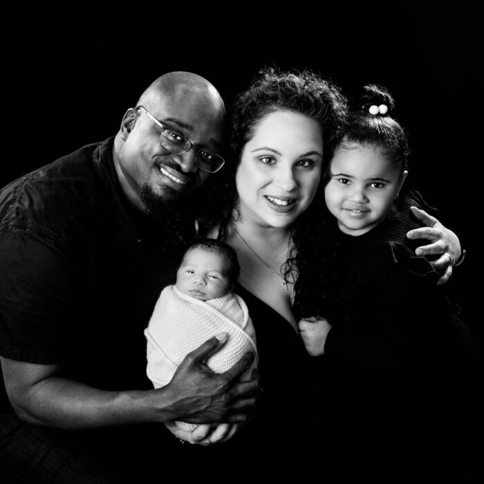 Parents, newborn baby and older sister during a black-and-white family portrait session