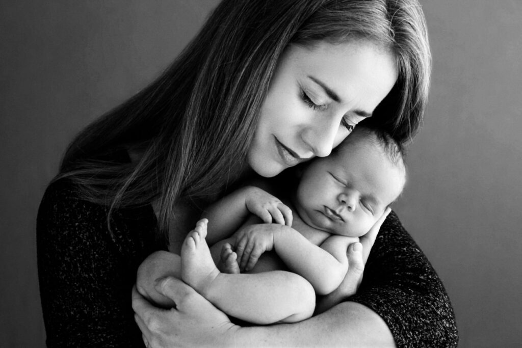 Mother holding her sleeping newborn baby during a black-and-white portrait sessio