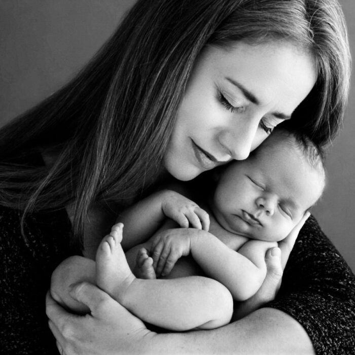 Mother holding her sleeping newborn baby during a black-and-white portrait sessio