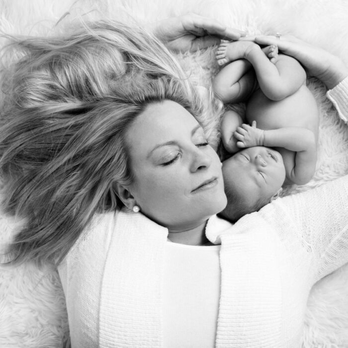 Mother lying beside her newborn baby during a black-and-white newborn photography session