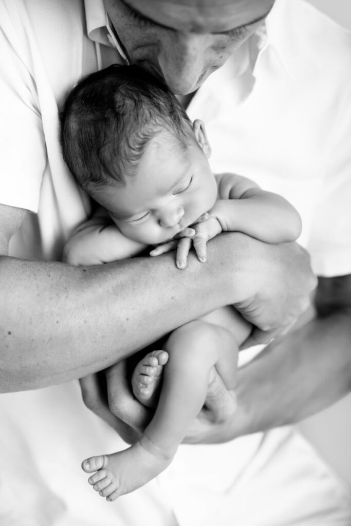 Father holding sleeping newborn baby during a black and white family portrait session