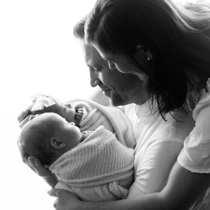 Parents holding newborn twins during a natural light family portrait session