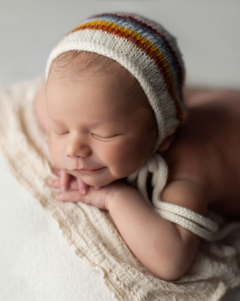 Sleeping newborn baby smiling while wearing a striped knit hat