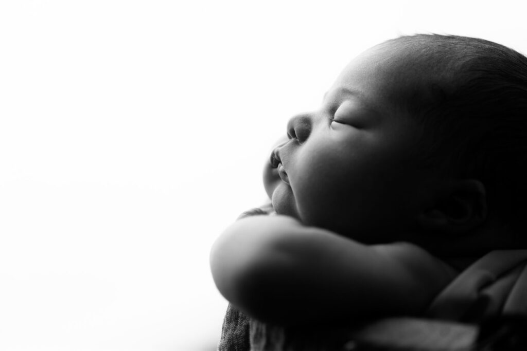 Close-up black and white profile portrait of a sleeping newborn baby