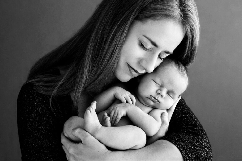 Mother holding her sleeping newborn baby during a black and white portrait session