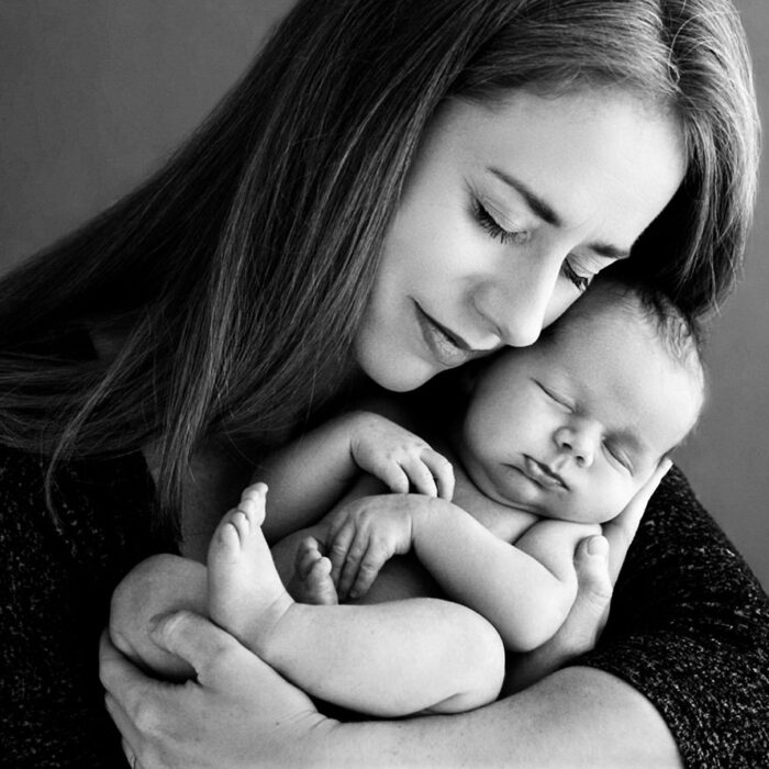 Mother holding her sleeping newborn baby during a black and white portrait session