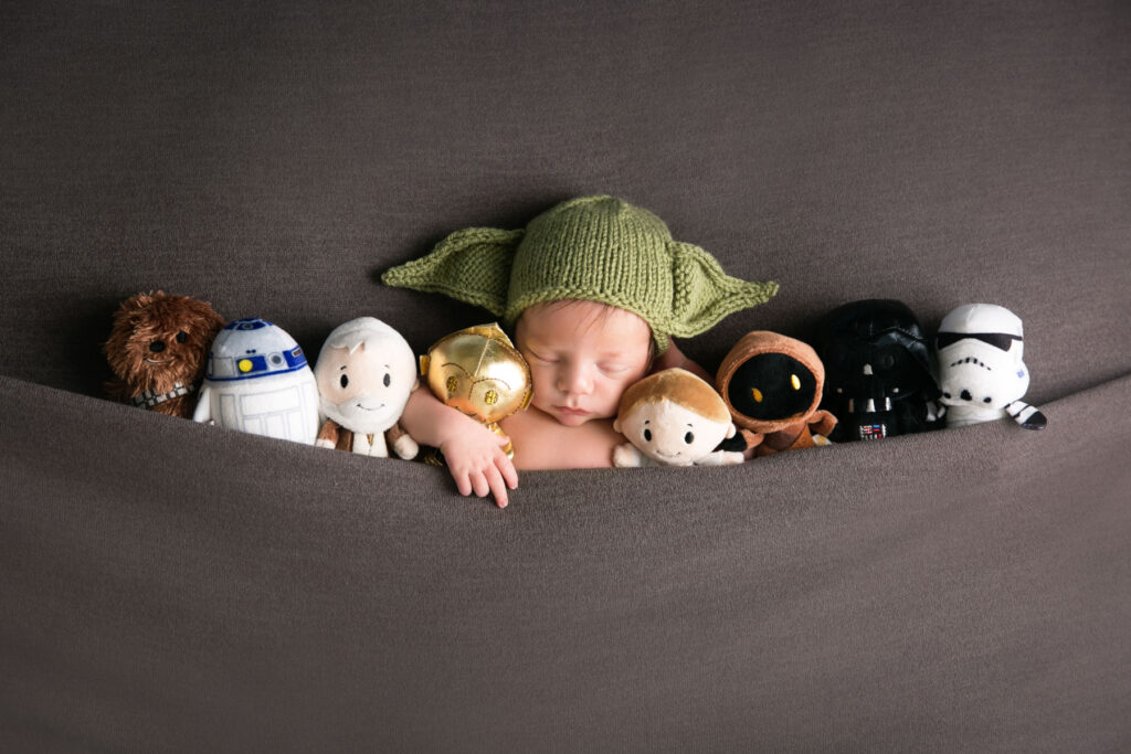 Sleeping newborn baby in a Star Wars themed portrait with character toys