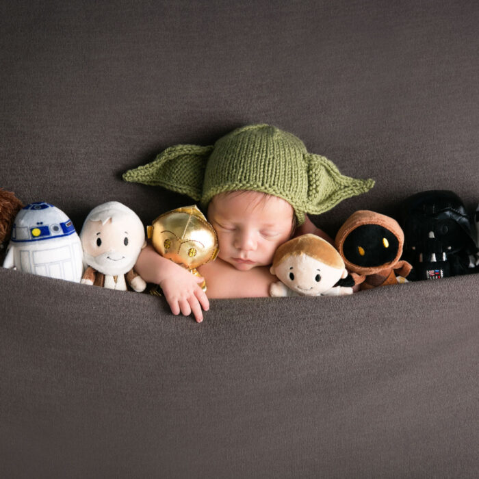 Sleeping newborn baby in a Star Wars themed portrait with character toys