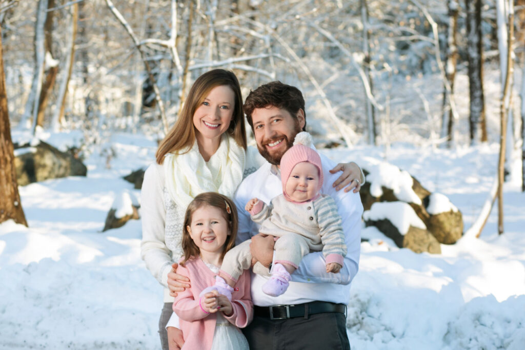 Family portrait outdoors in winter with parents and young children in the snow