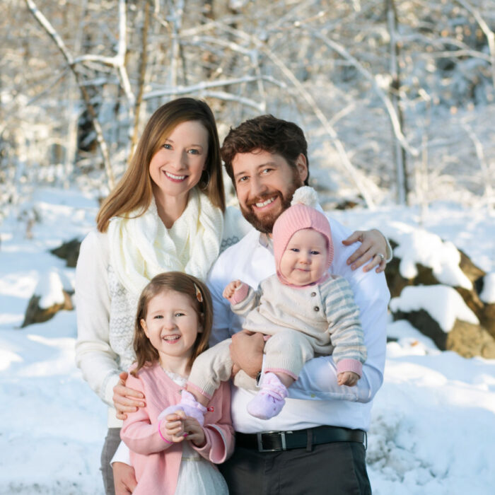 Family portrait outdoors in winter with parents and young children in the snow