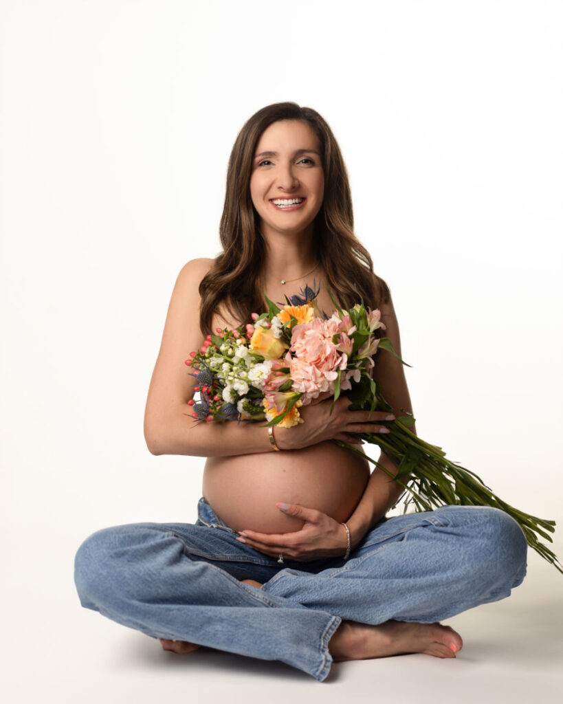 Pregnant mother holding a bouquet of flowers during a studio maternity portrait
