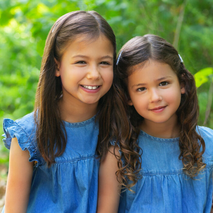 Two smiling sisters photographed outdoors during a Watch Me Grow portrait session.