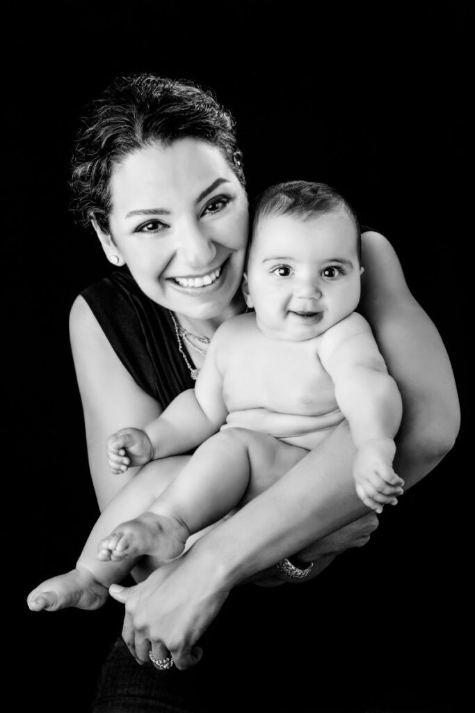 Mother holding her smiling baby daughter during a black-and-white studio portrait session