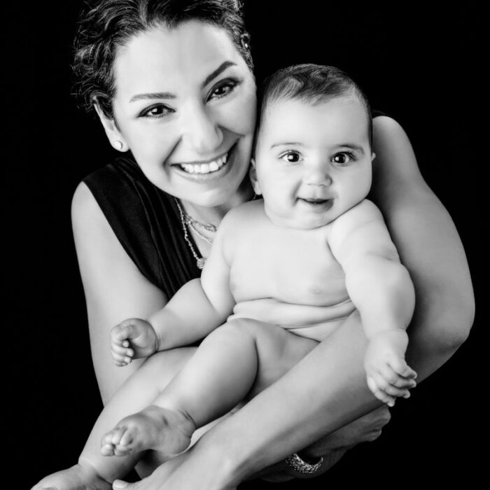 Mother holding her smiling baby daughter during a black-and-white studio portrait session
