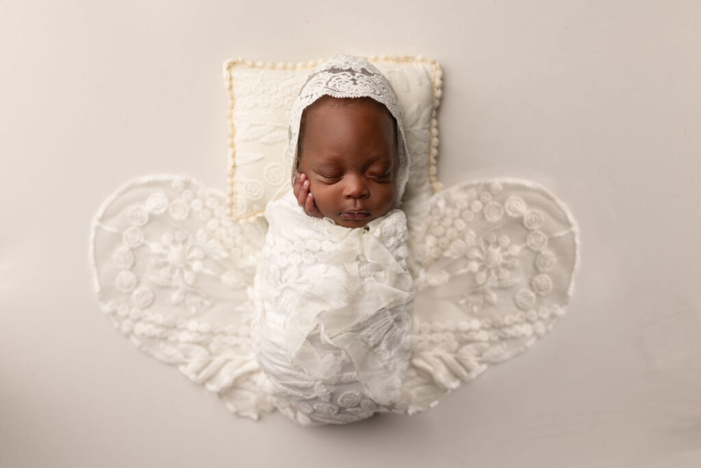 Sleeping newborn baby posed with delicate angel wings during a professional studio newborn session