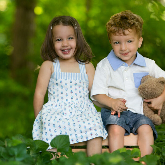 Young twins smiling together during outdoor Watch Me Grow photography session.