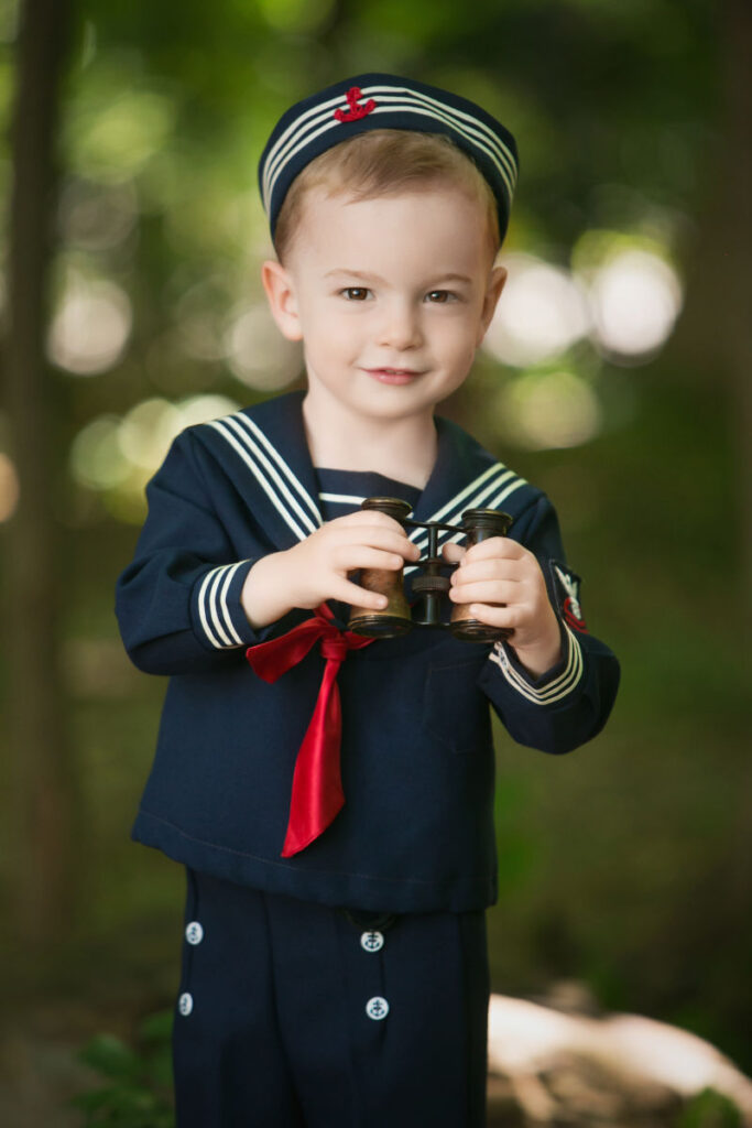 Young boy dressed in sailor outfit during children's portrait session.