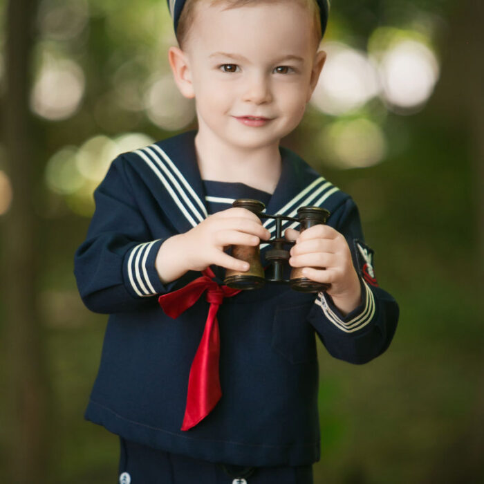 Young boy dressed in sailor outfit during children's portrait session.