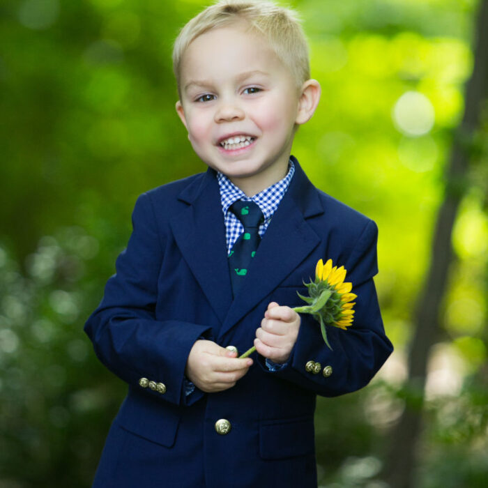 Young boy holding a sunflower during an outdoor portrait session near the studio.