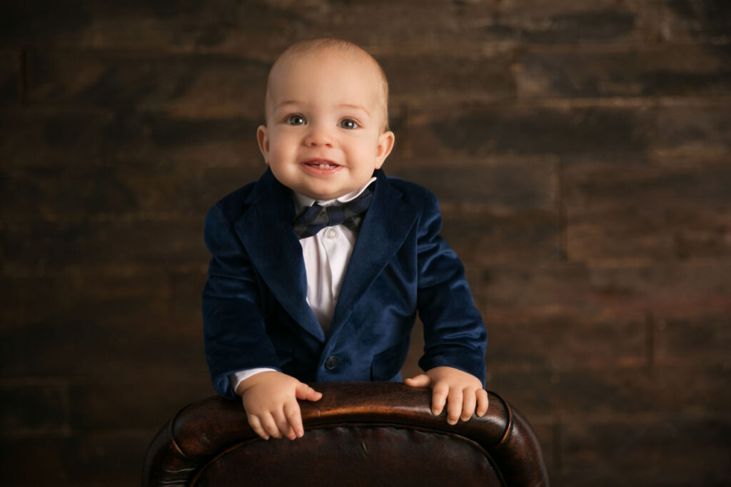 Smiling baby boy wearing a blue suit during a milestone portrait session
