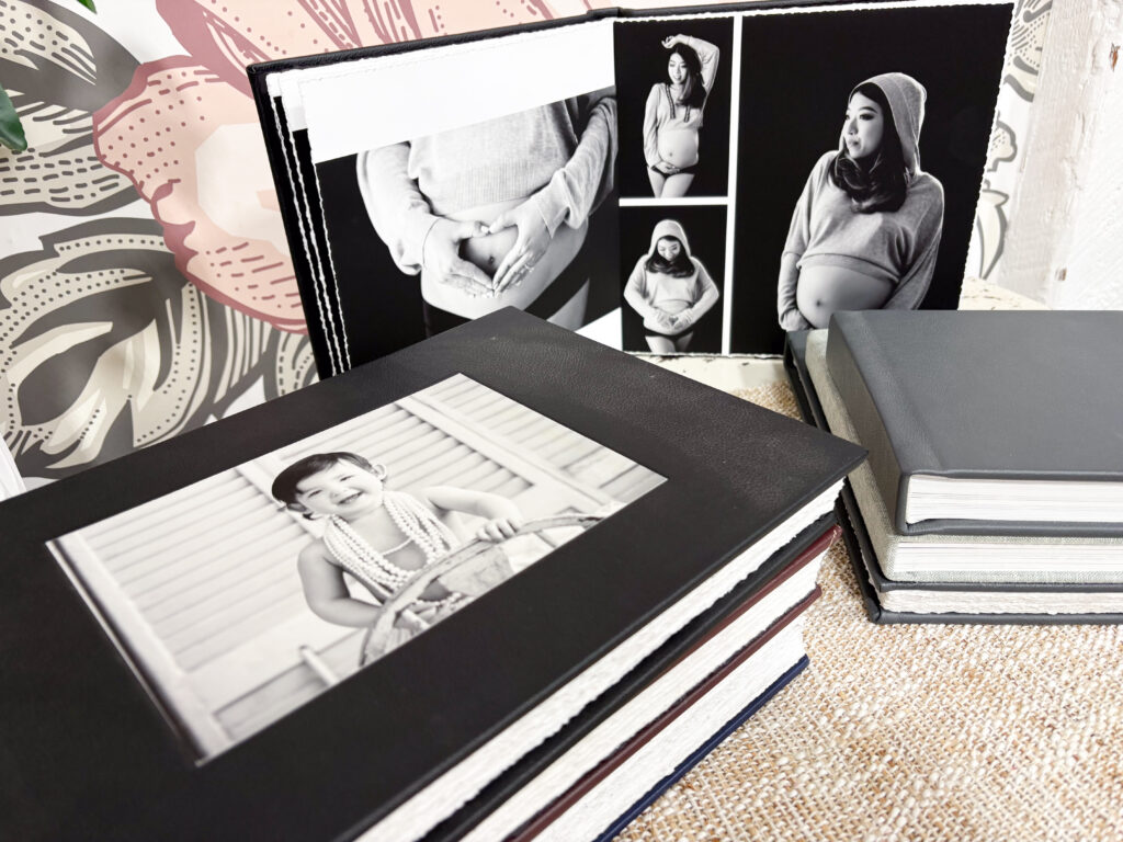 Sample portrait albums from Alternate Angles Photography showing a Baby Plan album and a single-session maternity album