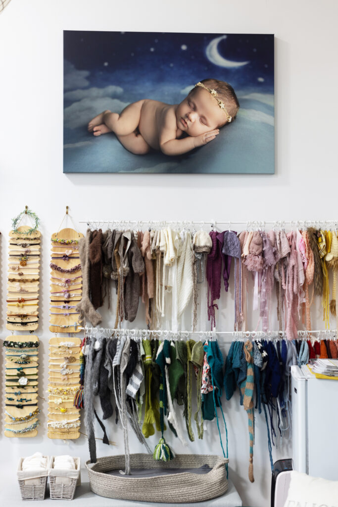 Newborn photography wardrobe with baby hats, headbands and studio wall portrait