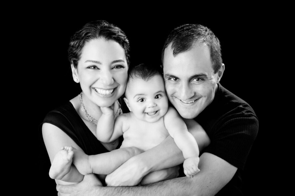 Parents holding their smiling baby during a black-and-white family portrait session