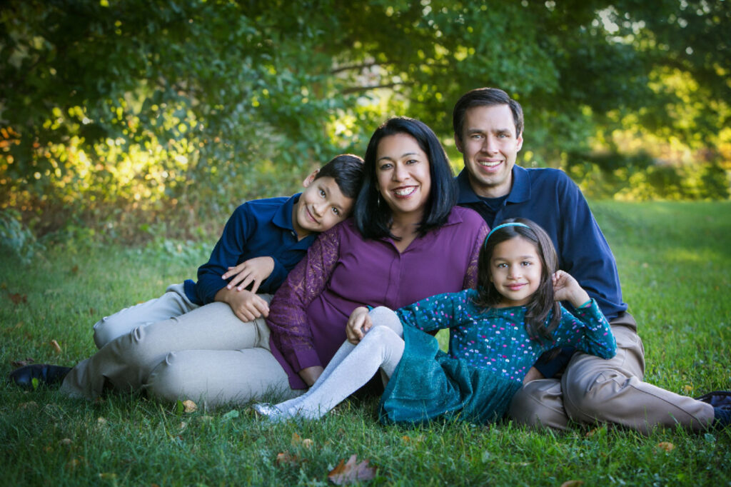 Family of four smiling together during an outdoor family portrait session in Norwood, MA