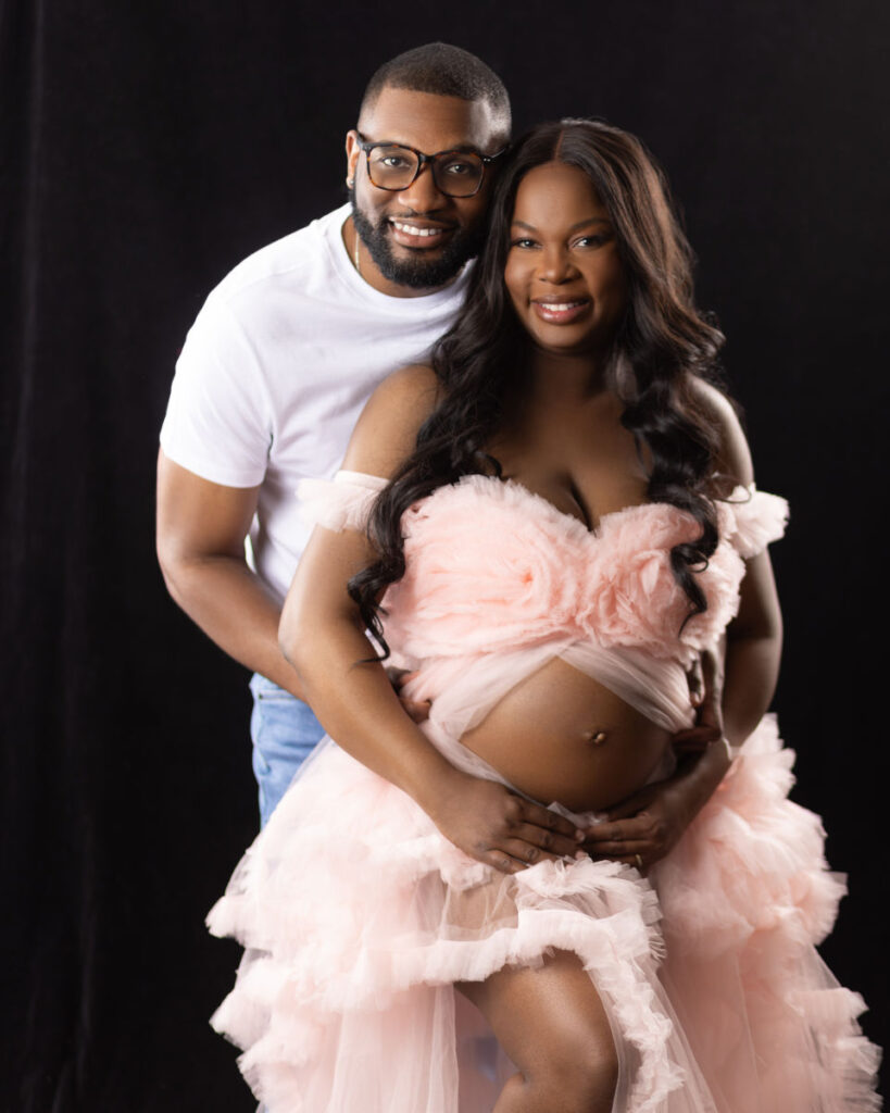 Expecting couple during a maternity portrait session with soft pink styling
