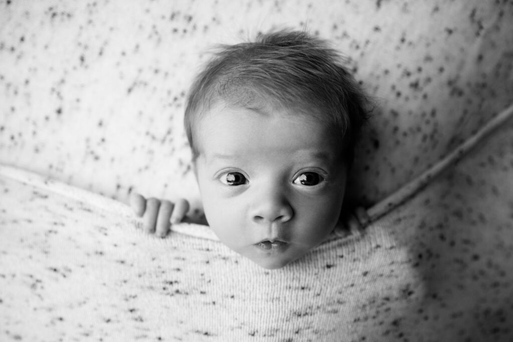 Close-up black-and-white portrait of an awake newborn with expressive eyes