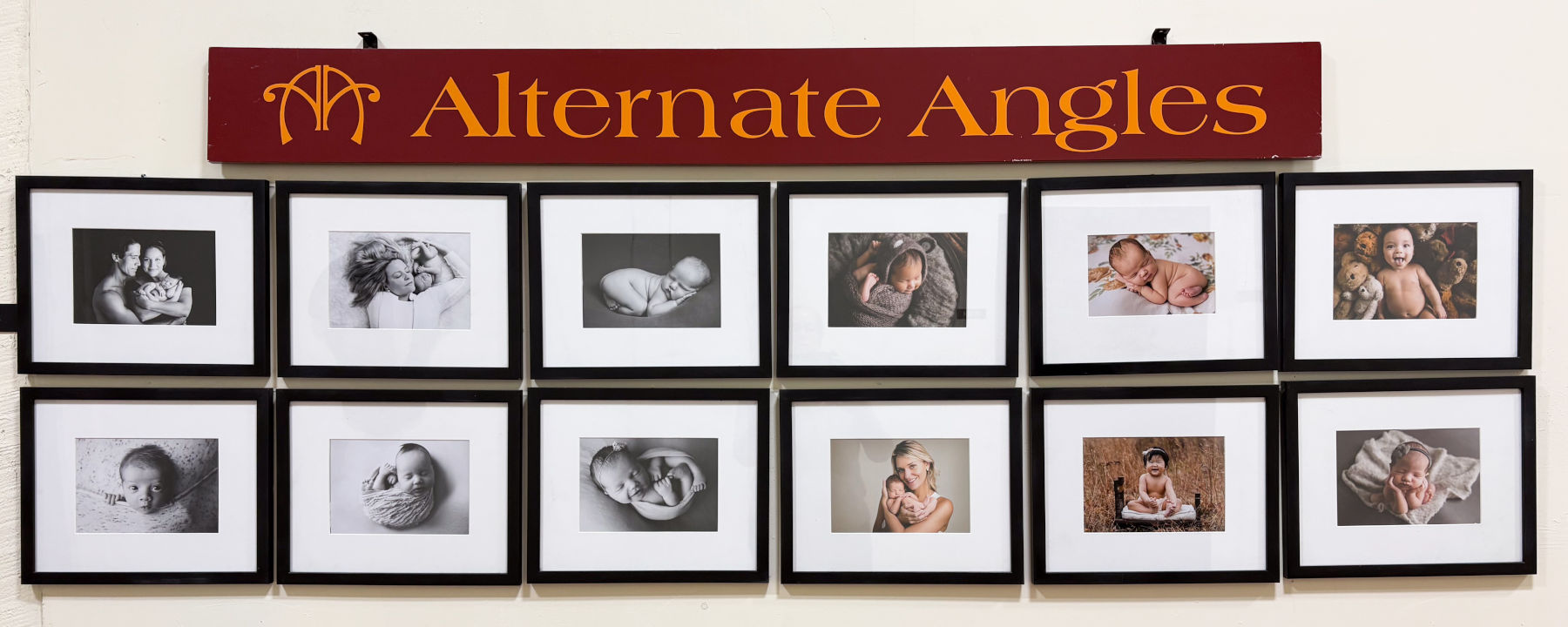 Wall display of newborn, baby and family portraits inside Alternate Angles Photography studio serving Greater Boston families