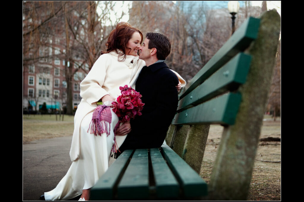Bride and groom sharing a romantic moment on a bench in the Boston Public Garden during a winter wedding at The Hampshire House