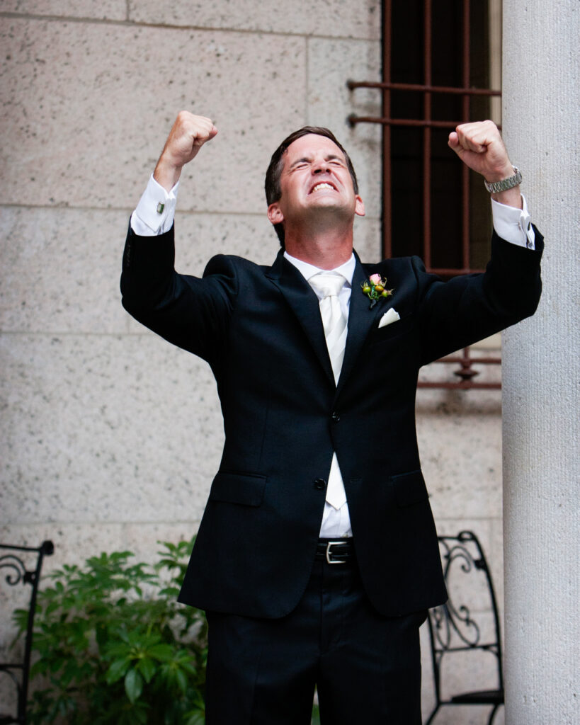 Groom celebrating with raised fists right after his wedding ceremony at the Boston Public Library