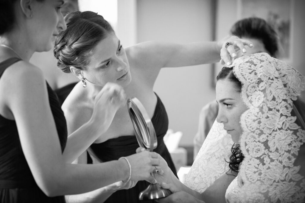 Maid of honor helping the bride with final touches to her lace veil while getting ready for a Newport Rhode Island wedding