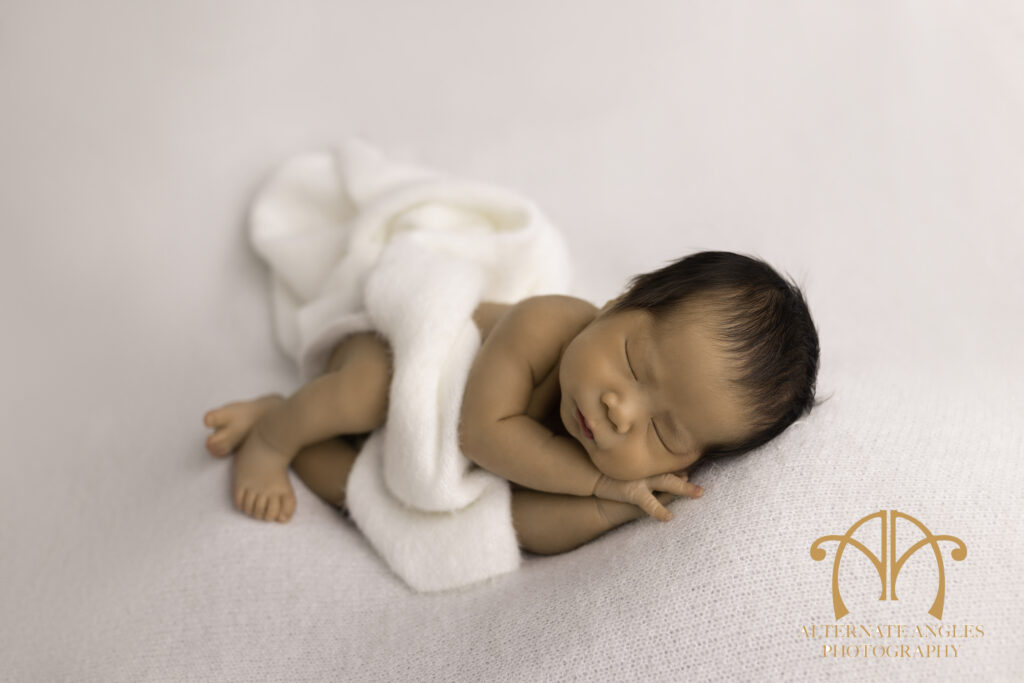 Newborn baby sleeping on white blanket during Boston studio newborn session