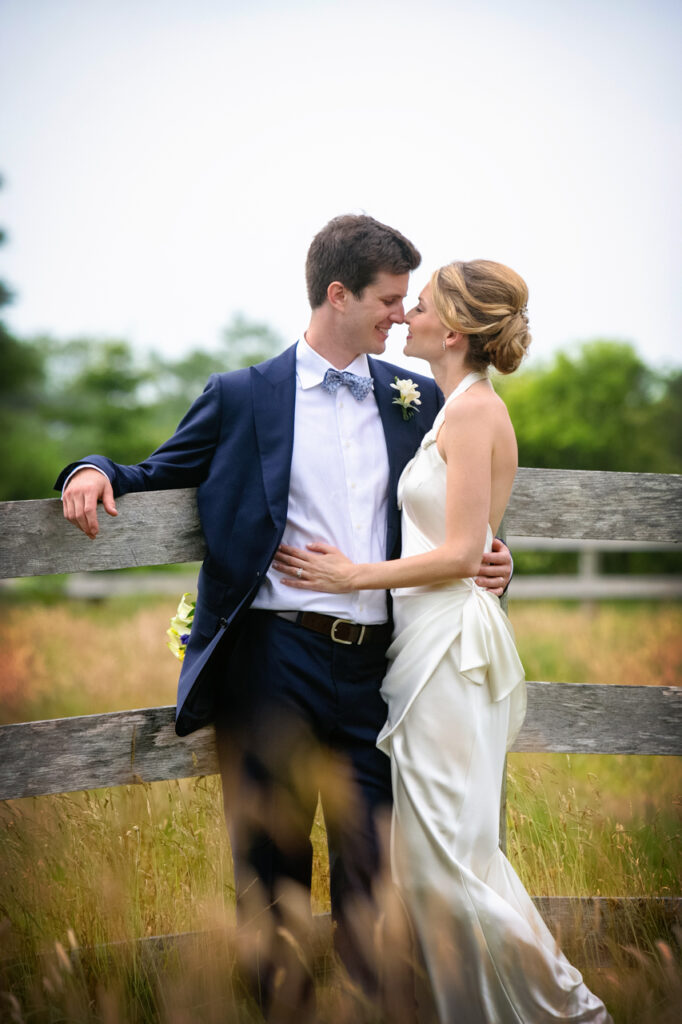 Bride and groom embracing by a wooden fence during a romantic Nantucket Massachusetts wedding portrait session