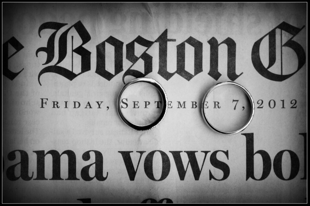 Wedding rings placed on a Boston Globe wedding announcement with the wedding date printed beneath them