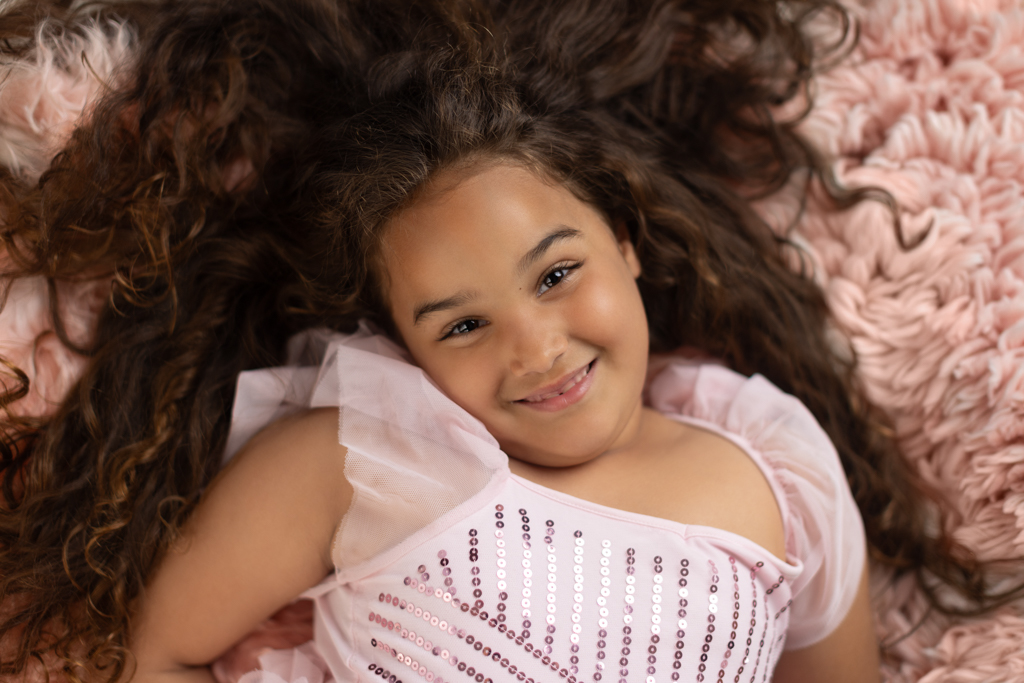 Overhead portrait of a smiling 6 year old girl wearing a pink princess dress during a child photography session