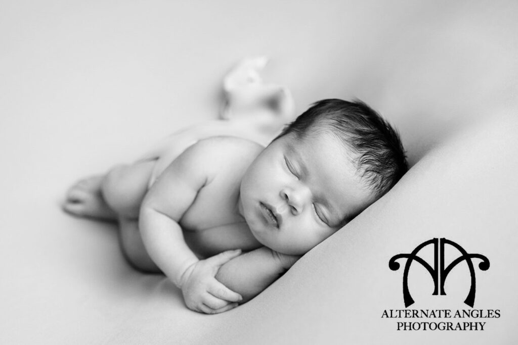 Black-and-white portrait of a sleeping newborn photographed by Alternate Angles Photography