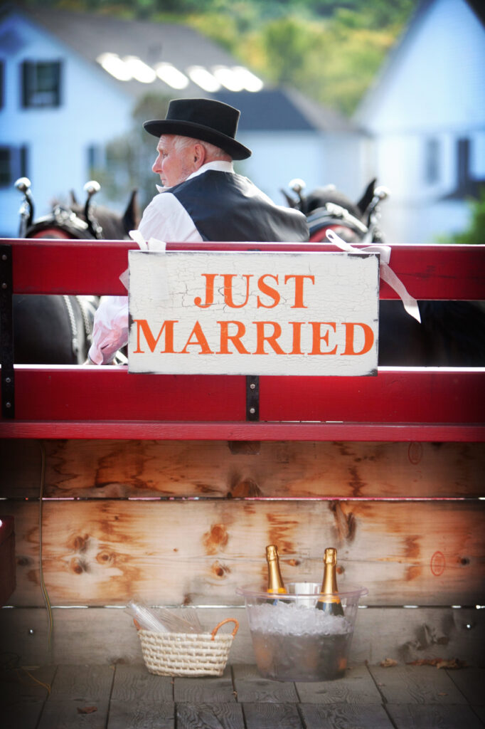 Horse and carriage driver waiting to transport the wedding party from the ceremony to the reception at a Quechee Vermont destination wedding