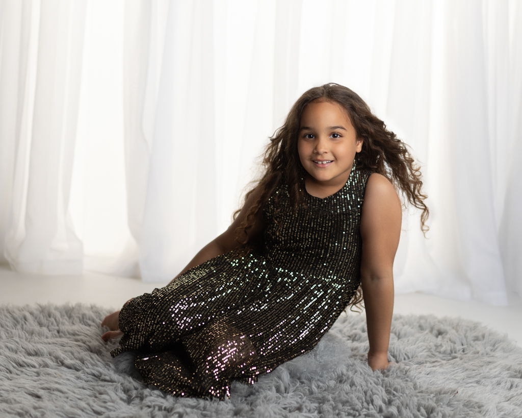 6 year old girl wearing a black sparkle dress posing during a professional child photography studio session