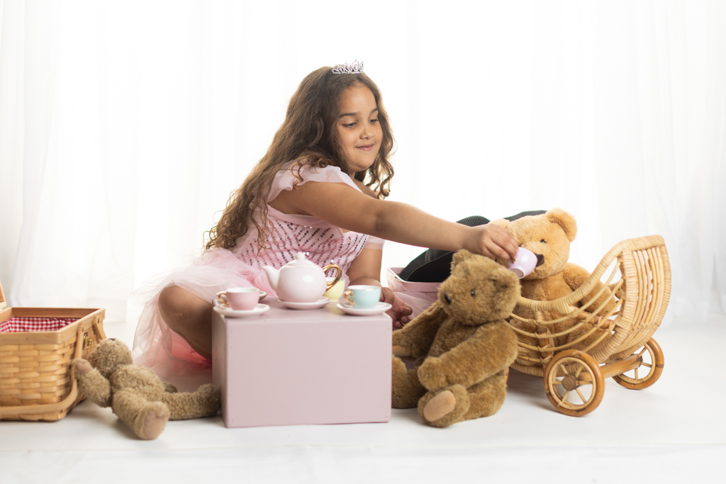 6 year old girl having a pretend tea party with teddy bears during a creative child portrait session
